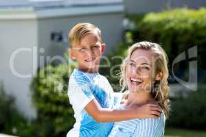 Smiling mother with son standing at yard
