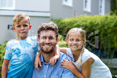 Portrait of smiling father with children at yard