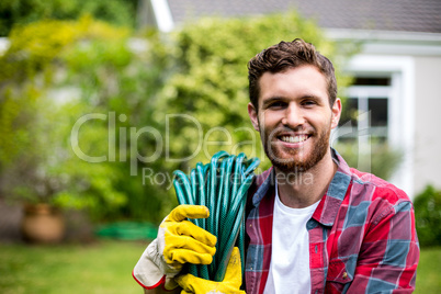 Smiling man carrying garden hose in backyard