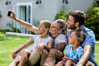 Happy mother taking selfie with family in yard