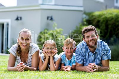 Front view of happy family lying in yard