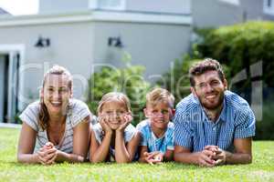 Front view of happy family lying in yard