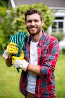 Smiling man carrying garden hose in yard