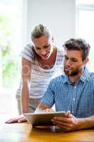 Man showing digital tablet to woman at home