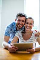 Portriat of smiling couple holding digital tablet