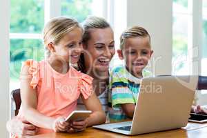 Smiling mother and children looking at laptop