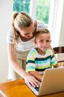 Happy mother and son using laptop at home