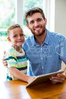 Smiling father and son with digital tablet at home