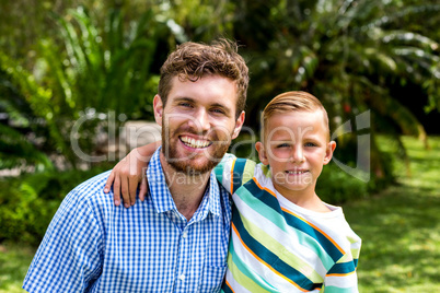 Portrait of smiling father and son in yard