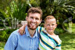 Portrait of smiling father and son in yard