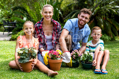 Smiling family with flower pots on grass at yard