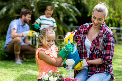 Mother and daughter watering flowers in yard