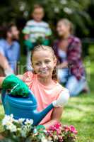 Smiling girl with watering can at yard