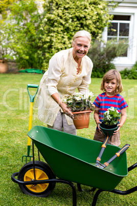 Grandmother with boy holding flower pots at yard