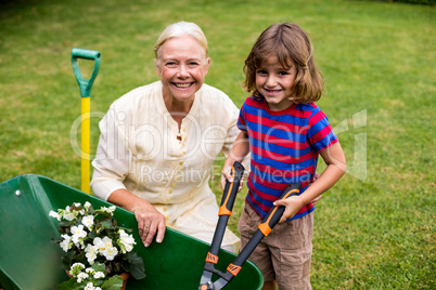 Boy with granny holding scissors over wheelbarrow at yard