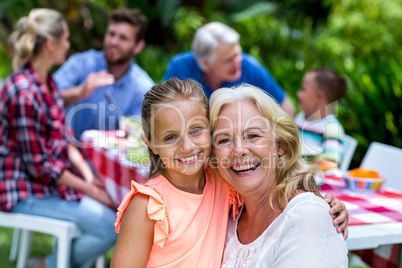 Smiling granny carrying girl during breakfast at yard