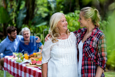 Happy mother-in-law and daughter-in-law standing in yard