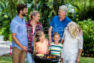 Family grilling food in barbeque at yard