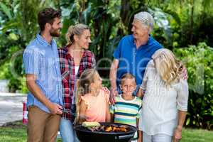 Family grilling food in barbeque at yard