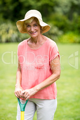 Senior woman with rake standing in yard