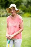 Senior woman with rake standing in yard