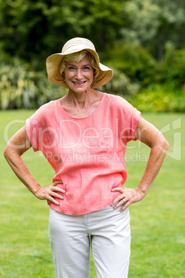Happy senior woman with ahnd on hip at yard