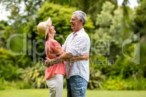 Senior couple embracing whiel standing in yard