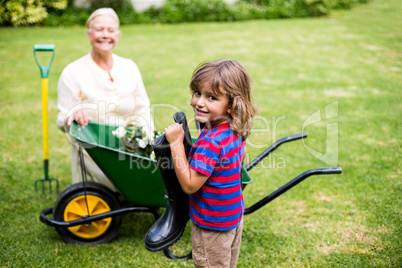 Boy holding wellington boots besides granny in yard