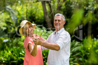 Senior couple holding hands while dancing in yard