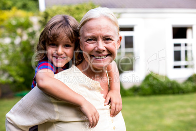 Granny piggybacking grandson in yard