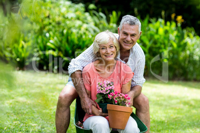 Happy senior couple with flower pots in yard