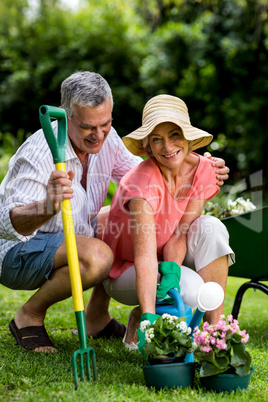 Smiling senior couple with gardening equipment at yard
