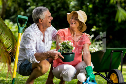Senior couple holding flower pot in yard