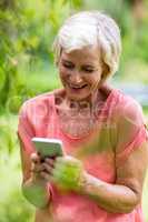Senior woman holding phone in yard