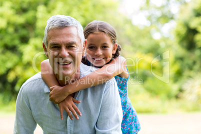 Grandfather carrying grandaughter in yard