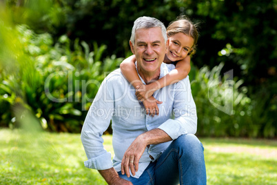 Grandfather and grandaughter smiling at yard