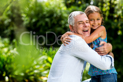 Grandfather hugging grandaughter at yard