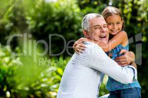 Grandfather hugging grandaughter at yard
