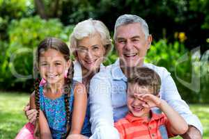 Children with grandparents sitting at yard