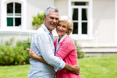 Senior couple embracing outside house at yard