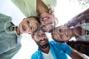 Smiling family forming huddle against sky