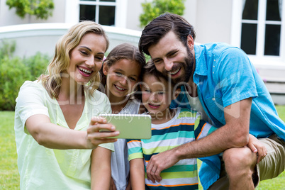 Mother taking selfie with family in yard