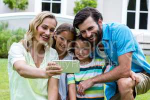 Mother taking selfie with family in yard