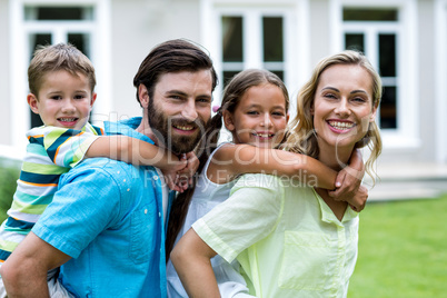 Parents piggybacking children in yard