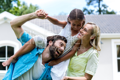 Father carrying daughter on shoulder in yard