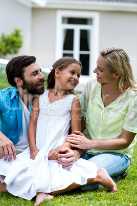 Girl with mother and father sitting in yard