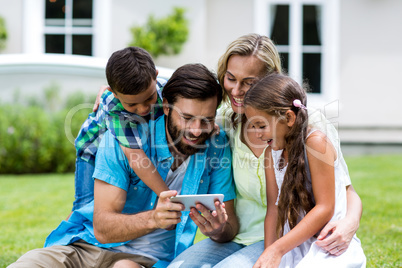 Happy family looking into mobile phone at yard