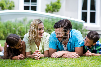 Smiling parents with children lying on grass in yard