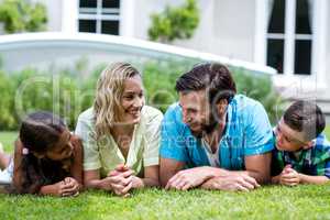 Smiling parents with children lying on grass in yard