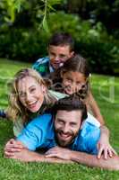 Smiling family lying on top of each other in yard